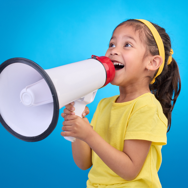 a girl in yellow dress speaking into megaphone