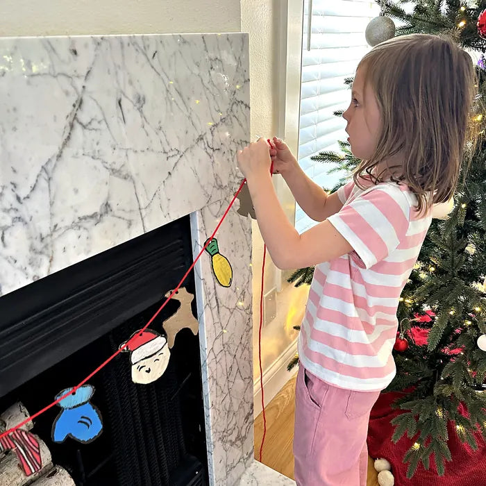 Girl hanging a handmade garland by the fireplace
