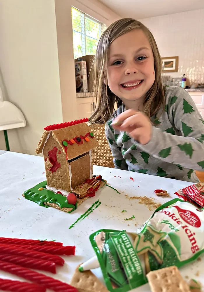Girl smiling next to her finished gingerbread house